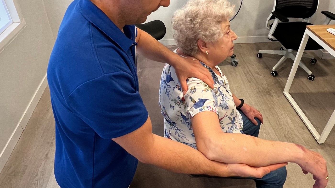 fisio sujetando el brazo de una persona mayor