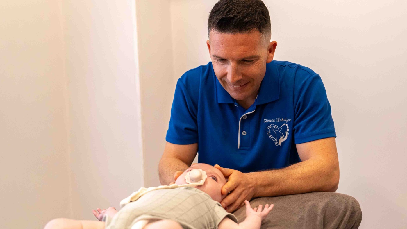 fisio tocando la cabeza de un bebe