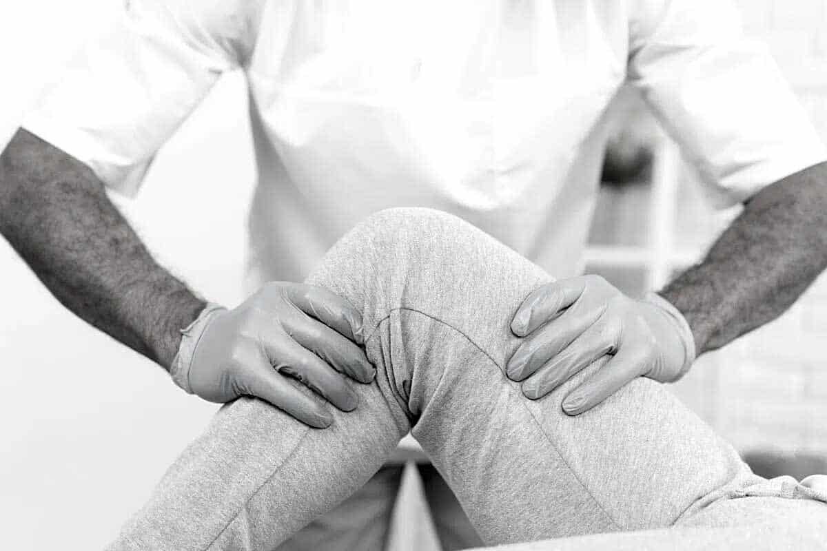 fisioterapeuta-rodilla-en-leganes Fisioterapeuta explorando la rodilla de un paciente tras un esguince de rodilla en Leganés.