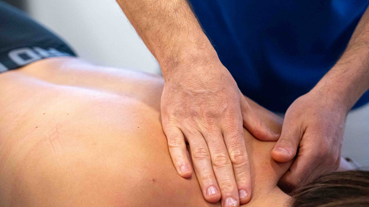 fisioterapeuta tocando cervicales de la paciente